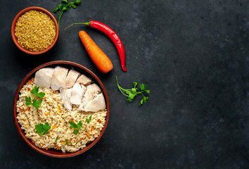 Bulgur with vegetables, chicken fillet on a stone background with copy space for your text. Healthy food
