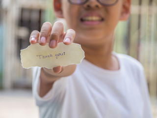 The boy holding piece of paper with the word Thank you in palm feeling happyness.