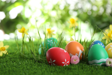 Fototapeta na wymiar Colorful Easter eggs and flowers in green grass. Space for text
