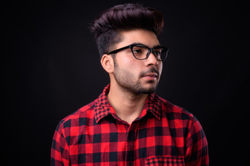 Young handsome Indian man against black background