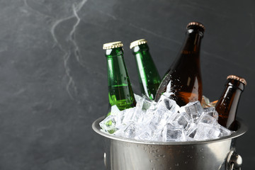 Metal bucket with beer and ice cubes on grey background, closeup. Space for text