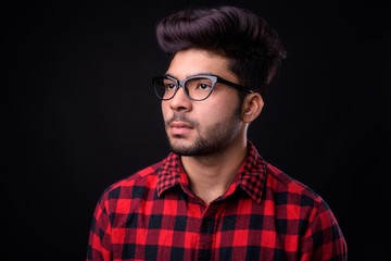 Young handsome Indian man against black background