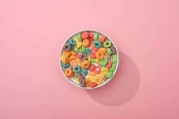 Tuinposter top view of bright colorful breakfast cereal in bowl on pink background © LIGHTFIELD STUDIOS