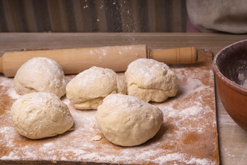 Balls of dough. Plywood cutting board, wooden flour sieve and wooden rolling pin - tools for making dough.