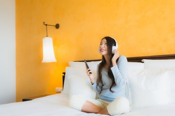 Portrait beautiful young asian woman using mobile cell phone with headphone for listen music