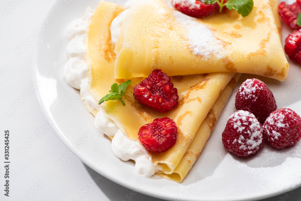 Wall mural close up view of tasty crepes with raspberries and whipped cream on plate