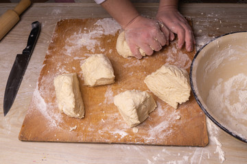 A woman kneads the dough. Plywood cutting board, wooden flour sieve and wooden rolling pin - tools for making dough.