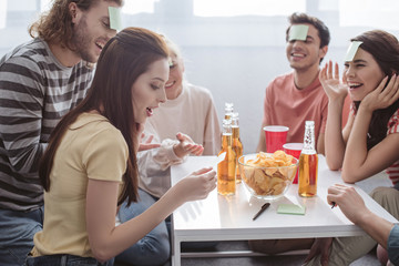 surprised girl looking at sticky note while playing name game with cheerful friends