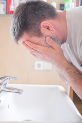 Obraz premium Man Washing Face In Bathroom Sink