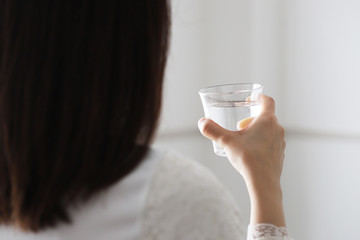 水分補給のためコップ一杯の水を飲む女性