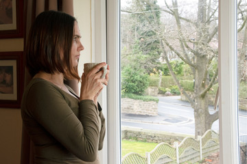 Woman stares out of window - obrazy, fototapety, plakaty