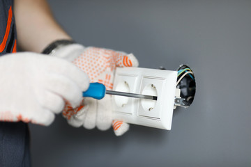 Repairman in gloves fixing socket with screwdriver - obrazy, fototapety, plakaty