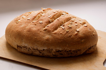 Freshly baked homemade buckwheat flour and whole grain corn bread. Bread sprinkled with oat flakes on a white background. Healthy gluten free food.