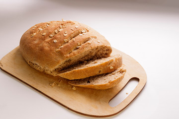 Freshly baked homemade buckwheat flour and whole grain corn bread. Bread sprinkled with oat flakes on a white background. Healthy gluten free food.