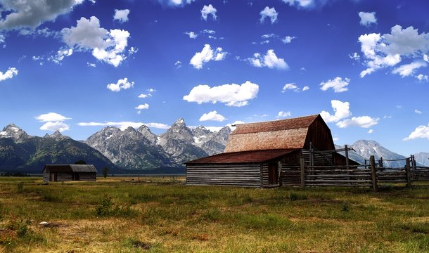 old barn in field in front of rugged grand teton mountains