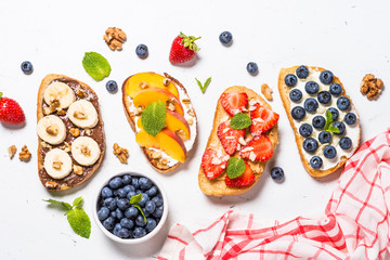 Sweet toast assortment with fresh fruit and berries on white.