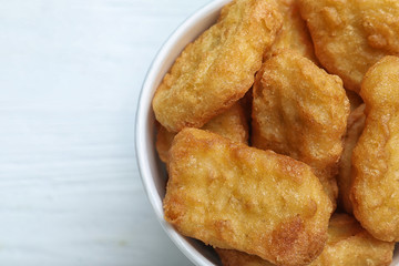 Bucket with tasty chicken nuggets on white wooden table, top view