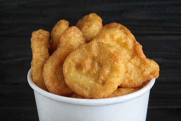 Bucket with tasty chicken nuggets on black background, closeup