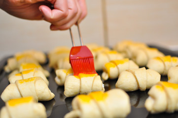 Process of making croissant rolls. Making domestic croissant rolls and using brush to add egg topping on rolls. French pastry goods