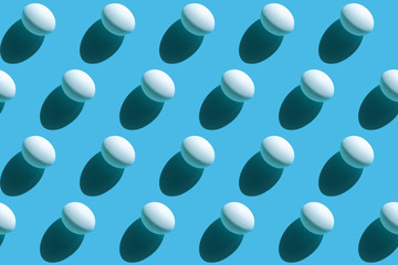 Repeating white eggs with a hard shadow on a blue background, easter background in pop art style