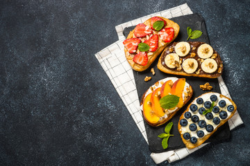 Sweet toast assortment with fresh fruit and berries on black.