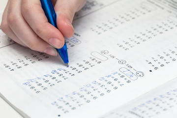 homework. The right hand of a child with a pen over a math notebook. Home schooling during quarantine