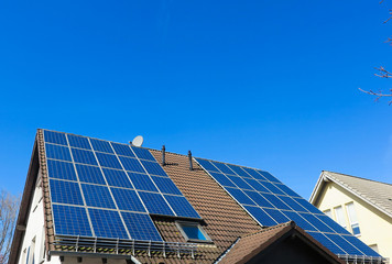 View on isolated german roof with solar panels against clear blue sky - Germany
