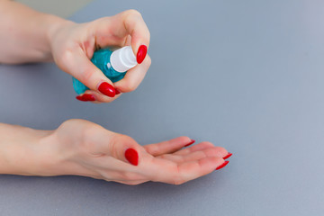 Woman push on dispenser and squeeze out soft soap gel on palm, closeup shot against flat background. Transparent liquid soap used for hand washing
