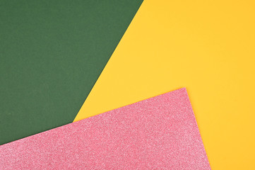 Yellow, green, pink glitter color paper background. Geometric flat lay. Empty space on monochrome cardboard