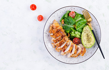 Trendy salad. Chicken grilled fillet with salad fresh tomatoes and avocado. Healthy food, ketogenic diet, diet lunch concept. Keto/Paleo diet menu. Top view, overhead, flat lay