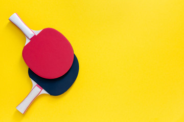 Red and black tennis ping pong rackets isolated on a yellow background, sport equipment for table...