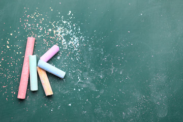 Pieces of color chalk on greenboard, flat lay. Space for text