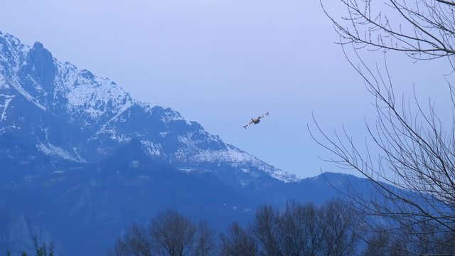 Lecco, Italy - March 2020: Firefighting aircraft Canadair flying in a cloudy sky during a fire emergency in the mountains near Lecco