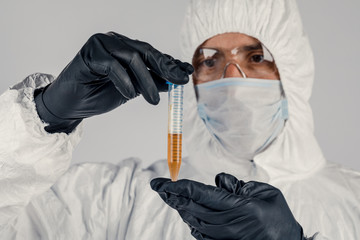 A test tube in a man's hand close-up , a man in a medical mask holding a bottle of red liquid....