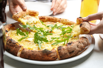 People taking pieces of delicious cheese pizza at white table, closeup