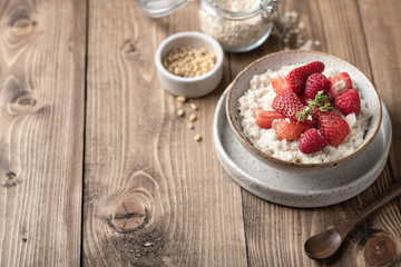 oatmeal with strawberries and raspberries in a bowl on a wooden background. Top view, place for text.