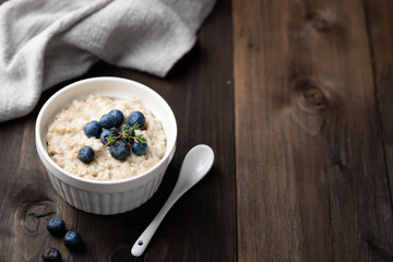 oatmeal with blueberries in a bowl on a wooden background. Top view, place for text.