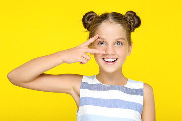 Young beautiful girl showing two fingers on yellow background