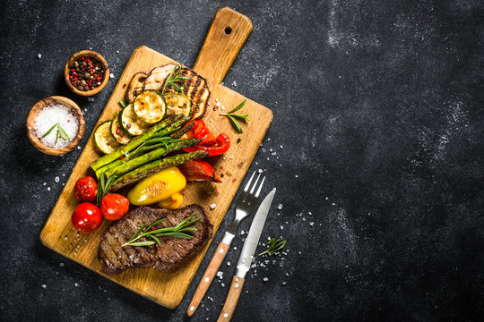 Beef Steak Grilled With Vegetables On Black Stone Table.