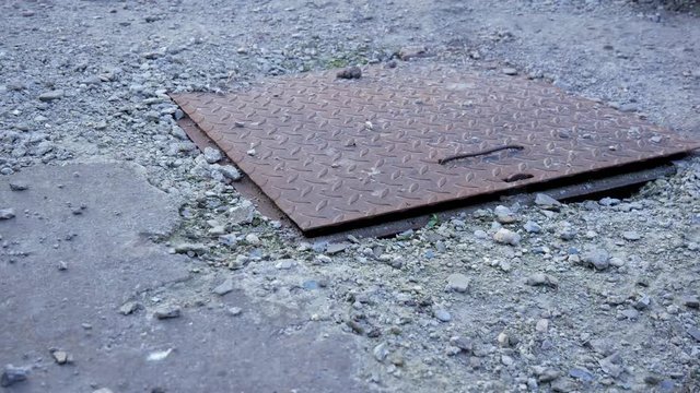 Rusty metal cover on crumbling concrete septic tank pan shot camera movement from left to right.