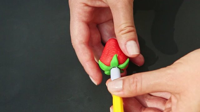 top view closeup woman hands make red strawberry shaped marzipan candy