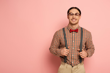 smiling male nerd in eyeglasses and suspenders on pink