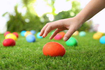 Fototapeta na wymiar Little child taking Easter egg from green grass, closeup