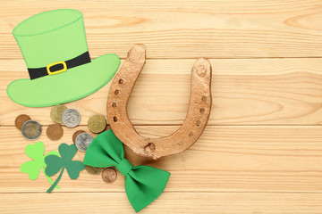 St.Patrick's Day. Paper clover leafs with golden horseshoe, hat and bow tie on brown wooden table