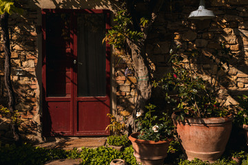 Italy, classic old Tuscan farmhouse red door with flowers and plants inside pots
