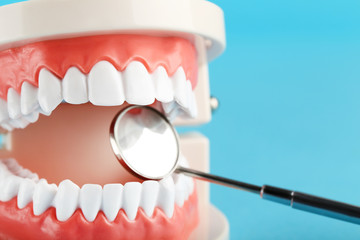 Fototapeta na wymiar Teeth model with dental mirror on blue background