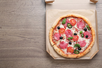 Delicious pizza Diablo in cardboard box on wooden background, top view. Space for text