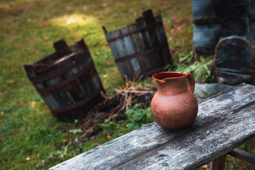 Obraz premium Traditional Estonian Water Jug on a Wooden Bench with Buckets on the background