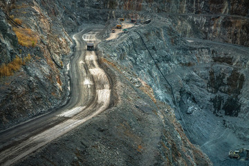 Yellow dump truck loading minerals copper, silver, gold, and other  at mining quarry.