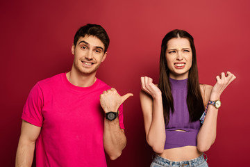 smiling boyfriend showing confused girlfriend on red